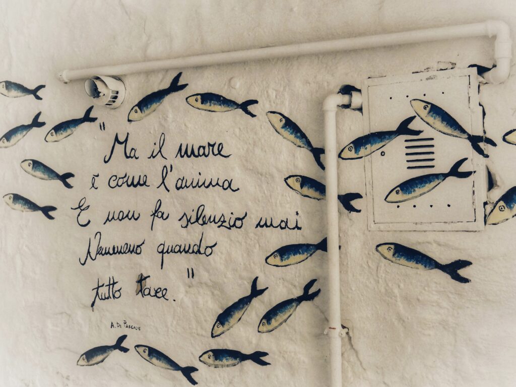 The streets, walls and doors of Polignano’s old town are decorated with poetry drawn by Guido Lupore, using the tag Guido il Flâneur. Photo the Puglia Guys for The Big Gay Podcast from Puglia