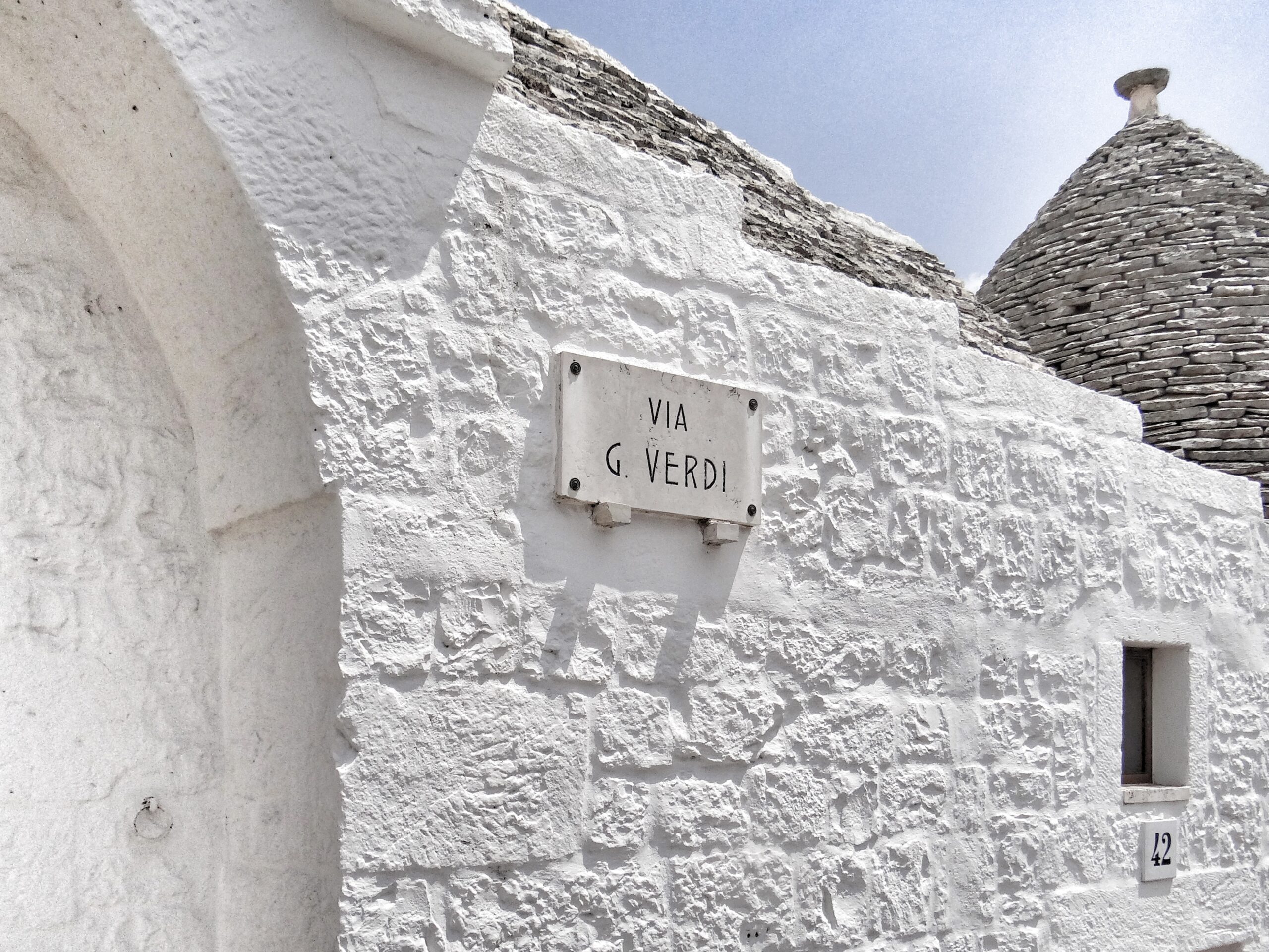 The wall of a dazzling white trullo in gay Puglia’s iconic Alberobello. The Big Gay Podcast from Puglia brings you their top tips for making the most of your visit to Alberobello.