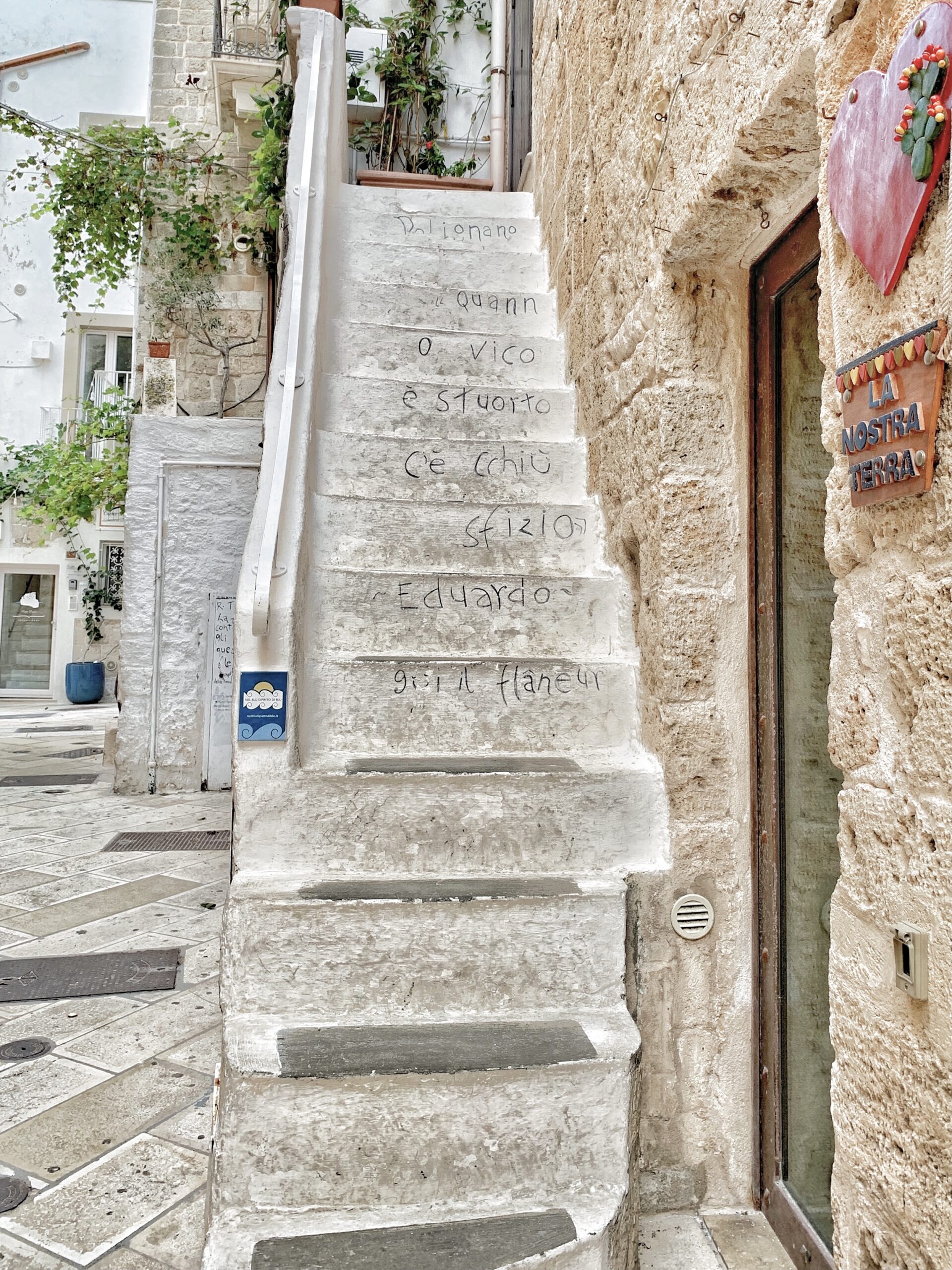 The streets, walls and doors of Polignano’s old town are decorated with poetry drawn by Guido Lupore, using the tag Guido il Flâneur. Photo the Puglia Guys for The Big Gay Podcast from Puglia