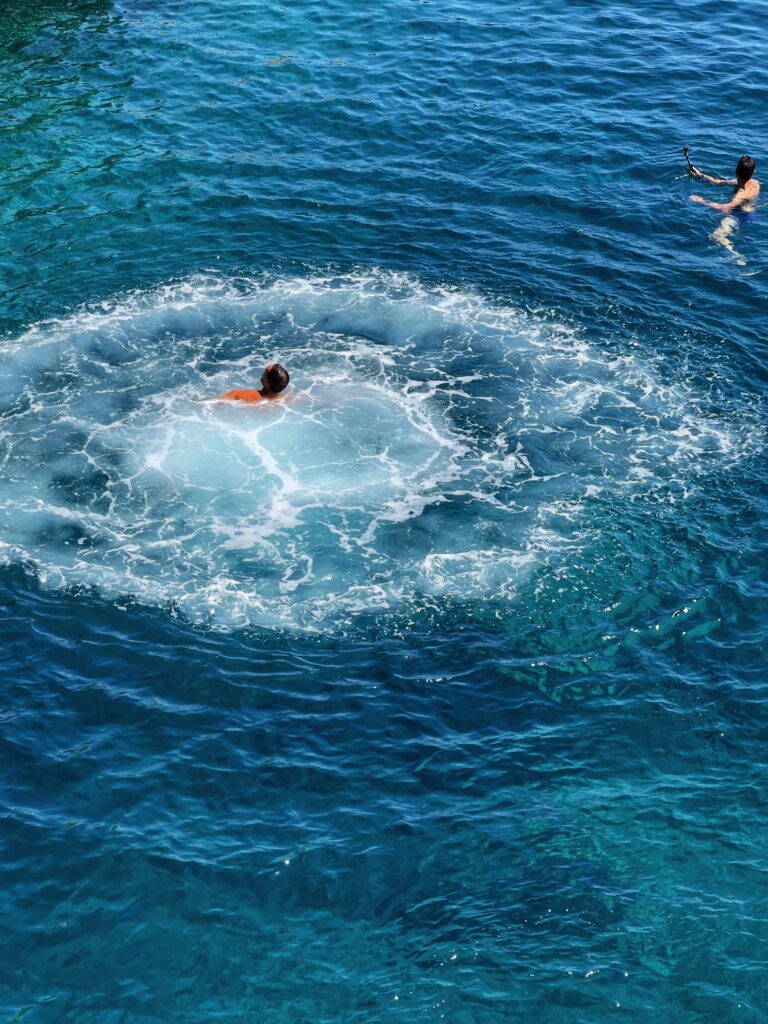 Jumping off the cliff at il Ciolo, Gagliano del Capo - one of Puglia’s most beautiful swimming spots, in a dramatic canyon underneath a bridge | Photo © the Puglia Guys for the Big Gay Podcast from Puglia guides to gay Puglia, Italy’s top gay summer destination