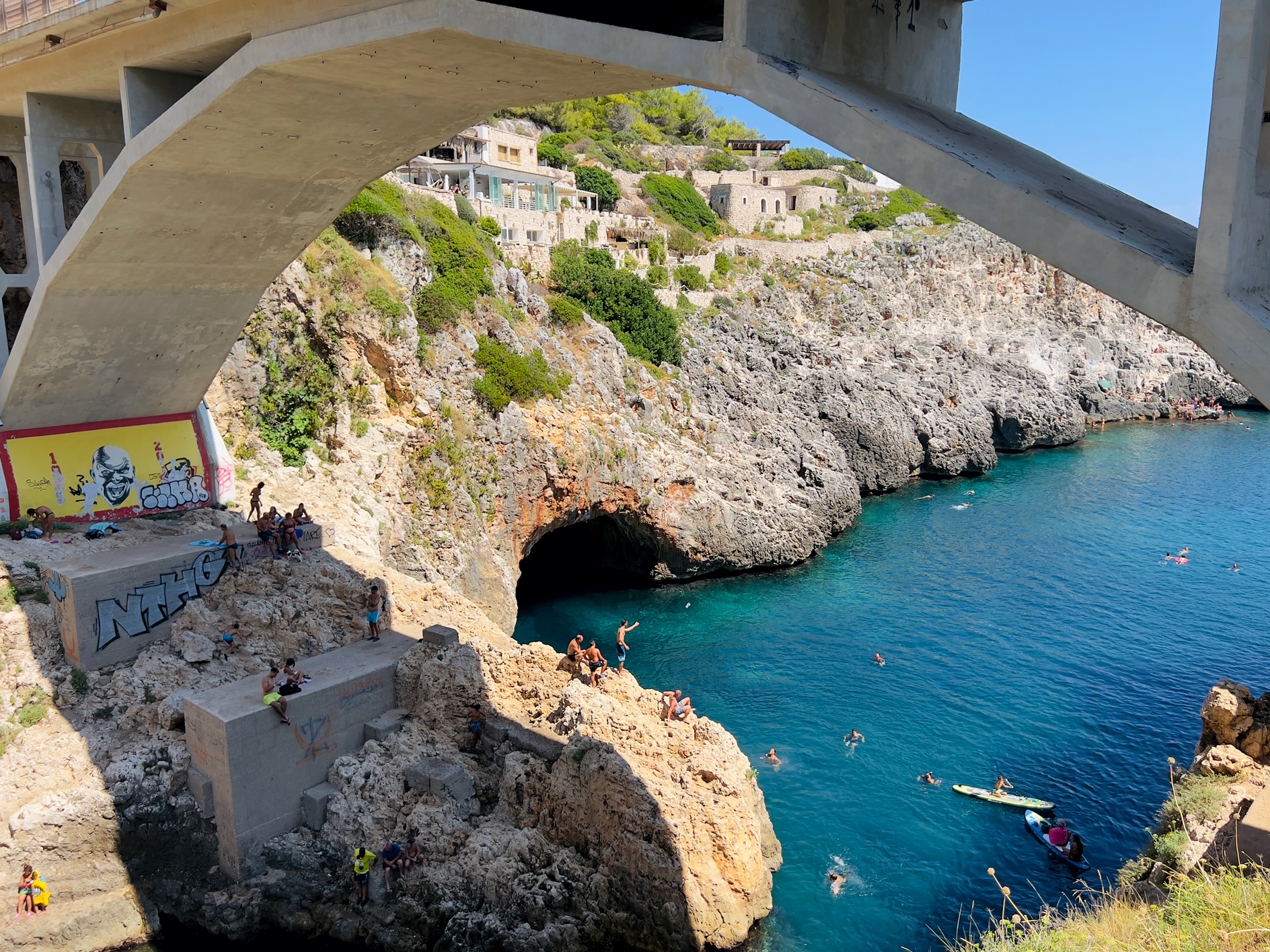 Jumping off the cliff at il Ciolo, Gagliano del Capo - one of Puglia’s most beautiful swimming spots, in a dramatic canyon underneath a bridge | Photo © the Puglia Guys for the Big Gay Podcast from Puglia guides to gay Puglia, Italy’s top gay summer destination