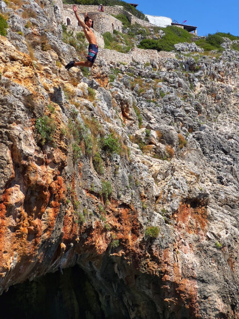 Jumping off the cliff at il Ciolo, Gagliano del Capo - one of Puglia’s most beautiful swimming spots, in a dramatic canyon underneath a bridge | Photo © the Puglia Guys for the Big Gay Podcast from Puglia guides to gay Puglia, Italy’s top gay summer destination