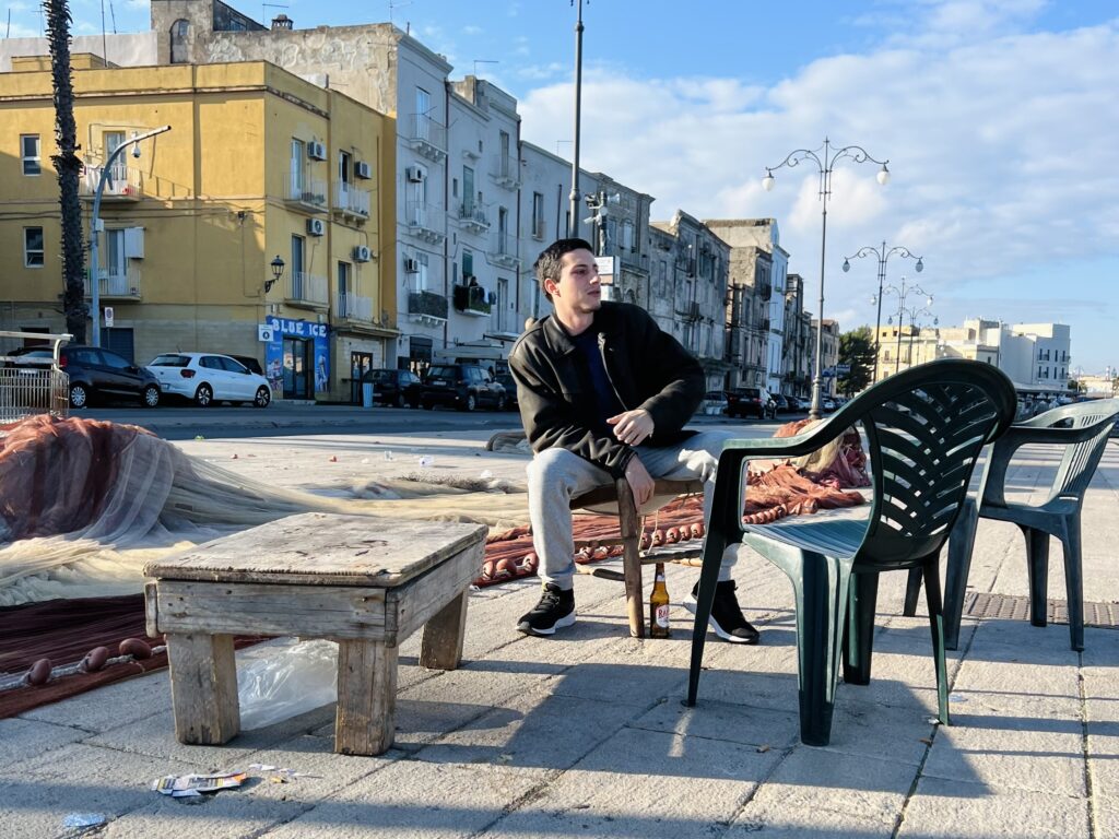 Marco, one of the Puglia Guys, sits by Taranto’s old port. Taranto. Borgo antico, the old town. The beauty underneath. Photo the Puglia Guys for the Big Gay Puglia Guide.